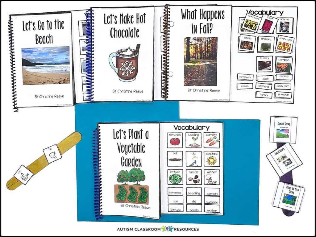 Four spiral-bound books for children with illustrated covers and vocabulary sheets are arranged on a table, along with a blue folder, a craft stick, and laminated picture cards for matching activities to support reading IEP goals for nonverbal students.