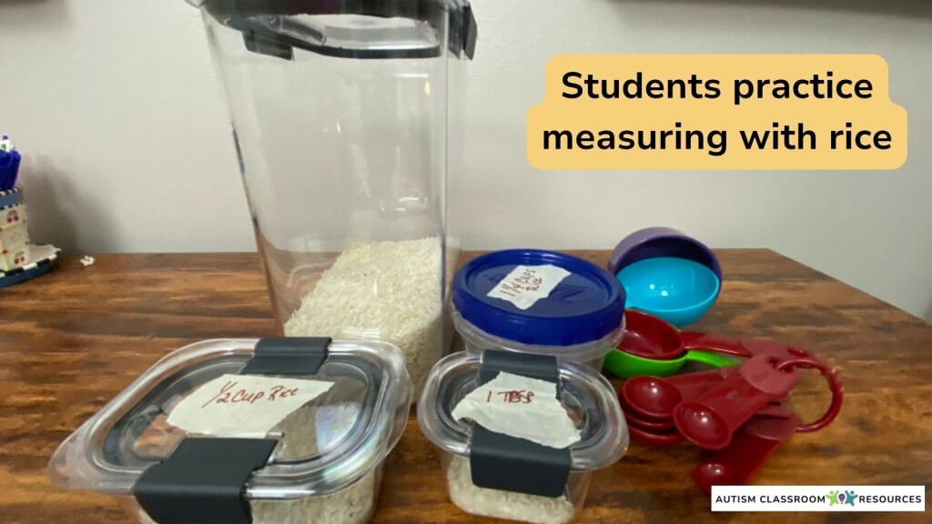 Students practice Measuring with rice and cups or spoons. Picture includes a large bin of rice with smaller sealed containers with masking tape used to identify how much of the rice (e.g., 1/4 cup) on the lid.  As well as the cups and spoons used to measure.